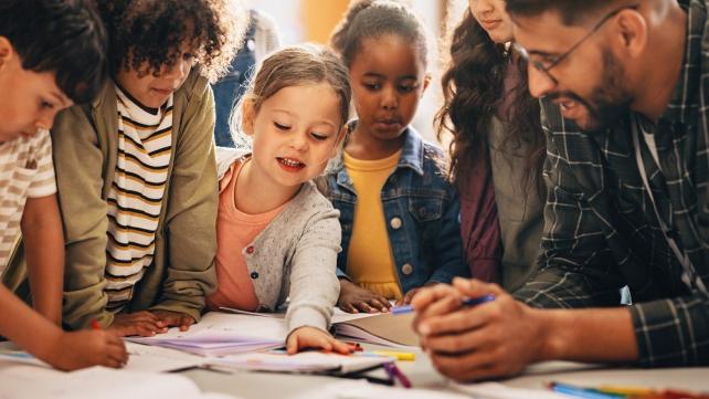 A group of children looking at a book Description automatically generated