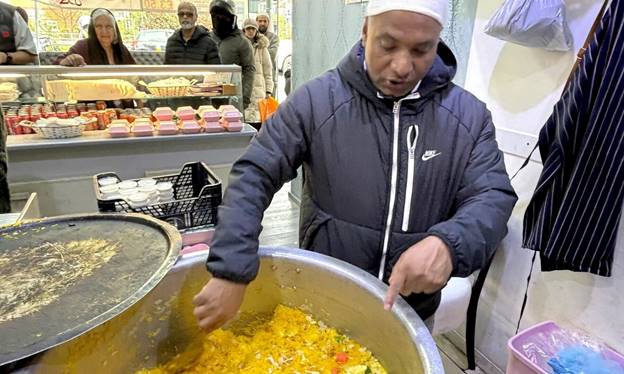 Ustad Zafar Pahalwan serves fresh zarda at his biryani shop in Ilford as customers line up for takeaway boxes.—Photo by the writer