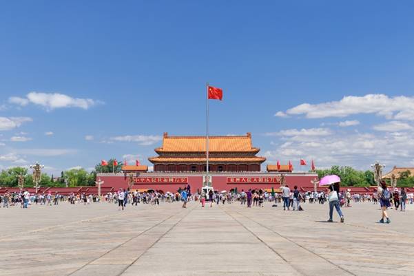 A group of people walking in front of Tiananmen Square Description automatically generated