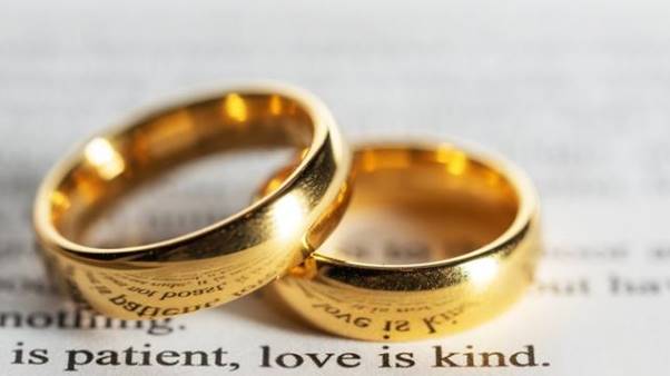 A pair of gold rings on a book Description automatically generated