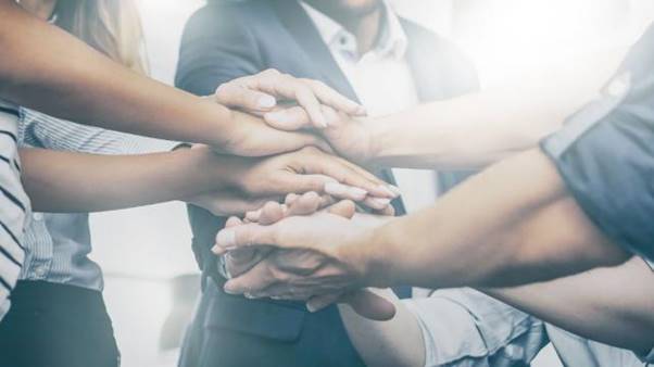 A group of people putting their hands together AI-generated content may be incorrect.