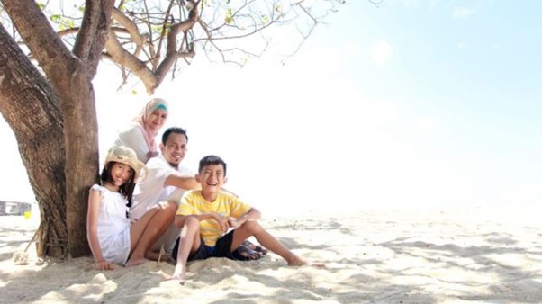 A family sitting on sand under a tree AI-generated content may be incorrect.