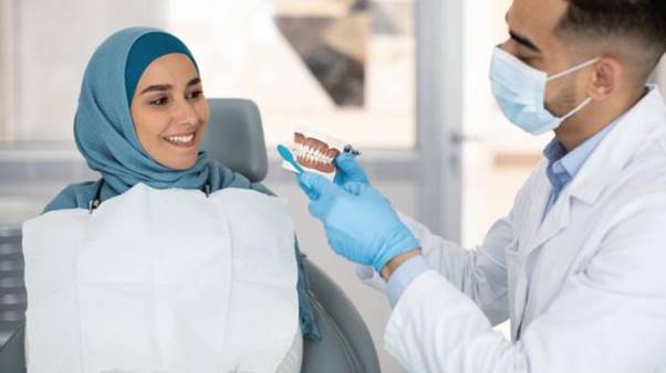 A dentist showing a person how to brush her teeth AI-generated content may be incorrect.