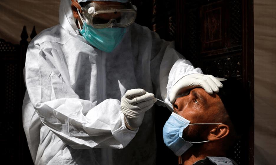 A paramedic wearing protective gear takes a nose-swab sample to be tested for the coronavirus in Karachi. &mdash; Reuters/File