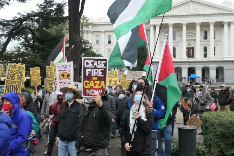 A group of people holding signs and flags Description automatically generated