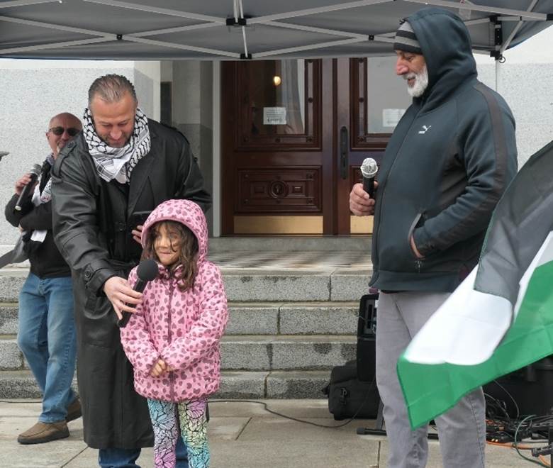A person holding a microphone and a child standing next to a person Description automatically generated