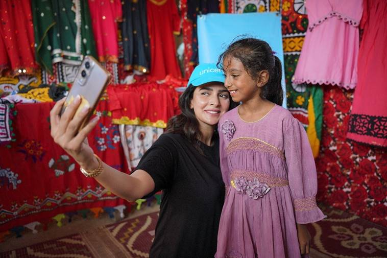 Actor Saba Qamar takes a selfie with a little girl at a womens clothing stall. &mdash;Unicef