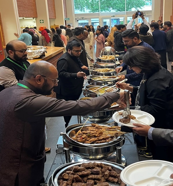 A group of people standing in a line with food in containers AI-generated content may be incorrect.