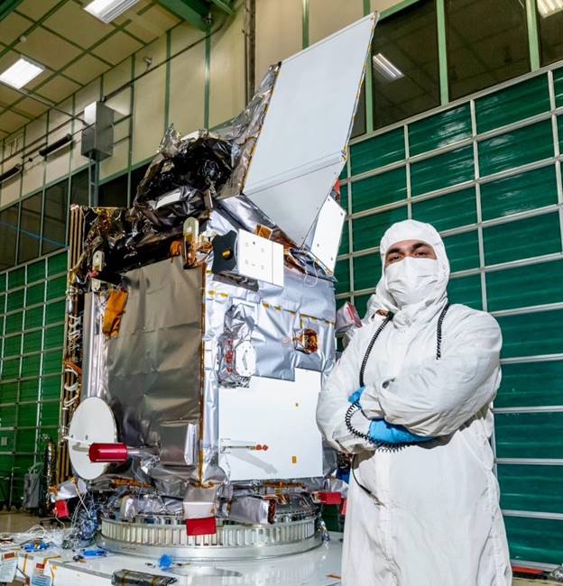 A person in white protective gear standing next to a large object AI-generated content may be incorrect.