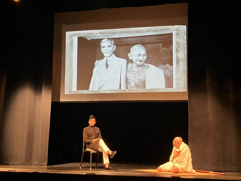 A person sitting on a stage with a person on his lap  Description automatically generated