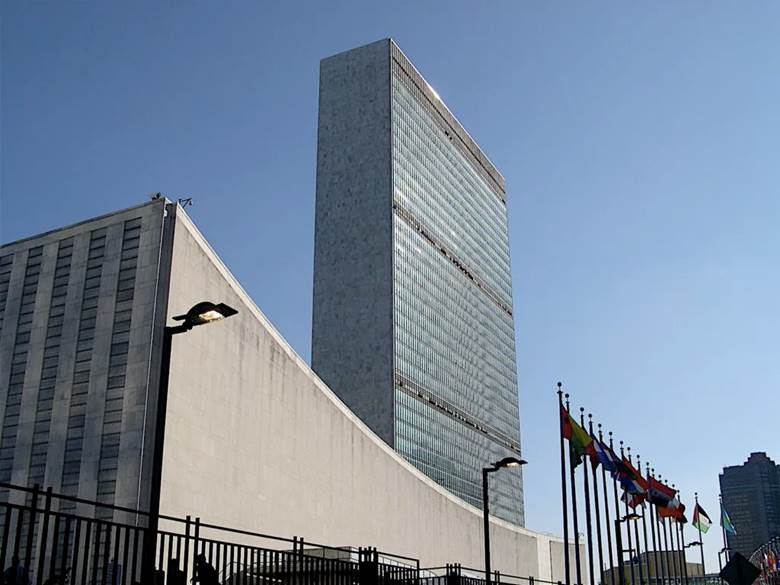 A tall building with flags in front of it Description automatically generated